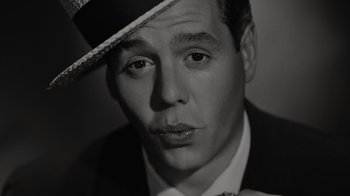 Movie still from “Lucy and Desi” (2022), directed by Amy Poehler – A black and white photo of a man wearing a hat; Extreme Close Up shot, High angle