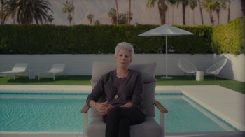 Movie still from “Lucy and Desi” (2022), directed by Amy Poehler – An older woman sitting in a chair near a pool; Medium shot, Over the shoulder angle