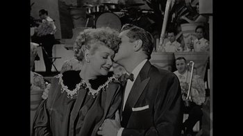 Movie still from “Lucy and Desi” (2022), directed by Amy Poehler – A man and a woman kissing each other in front of a crowd; Close Up shot, Over the shoulder angle