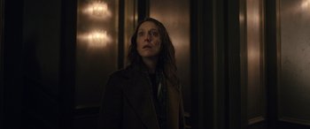 Movie still from “Luther: The Fallen Sun” (2023), directed by Jamie Payne – A woman standing in a dark room looking up at the ceiling; Medium shot, Low angle