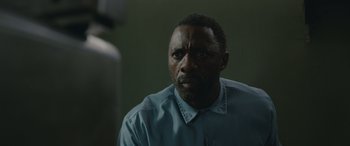 Movie still from “Luther: The Fallen Sun” (2023), directed by Jamie Payne – A man in a blue shirt is looking at the camera; Close Up shot, Over the shoulder angle