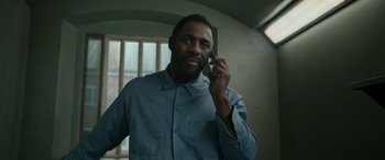Movie still from “Luther: The Fallen Sun” (2023), directed by Jamie Payne – A man talking on a cell phone while wearing a blue shirt; Close Up shot, Low angle