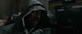 Movie still from “Luther: The Fallen Sun” (2023), directed by Jamie Payne – A man wearing a rain jacket and a hood; Close Up shot, Over the shoulder angle