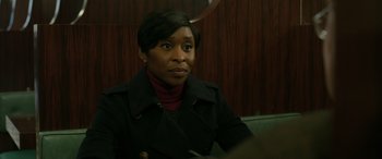 Movie still from “Luther: The Fallen Sun” (2023), directed by Jamie Payne – A woman in a black jacket sitting on a couch; Close Up shot, Over the shoulder angle