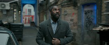 Movie still from “Luther: The Fallen Sun” (2023), directed by Jamie Payne – A man in a suit and tie standing on a street; Medium shot, Low angle