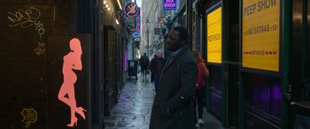 Movie still from “Luther: The Fallen Sun” (2023), directed by Jamie Payne – A man standing in the middle of an alley way; Medium shot, Over the shoulder angle