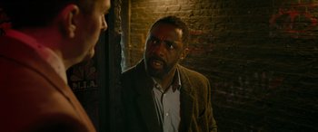 Movie still from “Luther: The Fallen Sun” (2023), directed by Jamie Payne – A man with a beard and a jacket on; Close Up shot, Over the shoulder angle