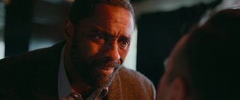 Movie still from “Luther: The Fallen Sun” (2023), directed by Jamie Payne – A person wearing a suit and tie; Close Up shot, Over the shoulder angle