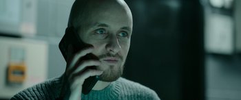 Movie still from “Luther: The Fallen Sun” (2023), directed by Jamie Payne – A man with a bald head talking on a cell phone; Close Up shot, Low angle