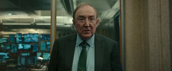 Movie still from “Luther: The Fallen Sun” (2023), directed by Jamie Payne – An older man wearing a suit and tie; Close Up shot, Over the shoulder angle