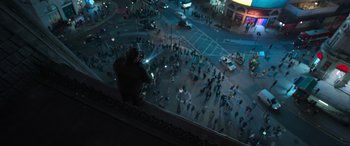 Movie still from “Luther: The Fallen Sun” (2023), directed by Jamie Payne – A man sitting on a ledge looking down at a crowd of people; Extreme Wide shot, High angle