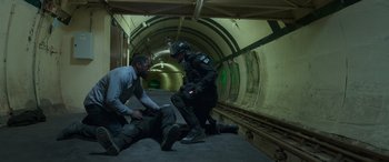 Movie still from “Luther: The Fallen Sun” (2023), directed by Jamie Payne – Two men in a tunnel with one of them being helped by another man; Wide shot, High angle