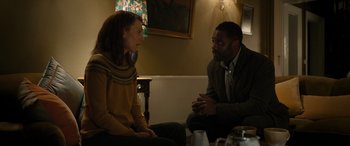 Movie still from “Luther: The Fallen Sun” (2023), directed by Jamie Payne – A man and a woman sitting in a room talking; Medium shot, Over the shoulder angle