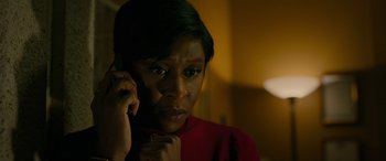Movie still from “Luther: The Fallen Sun” (2023), directed by Jamie Payne – A woman in a red shirt talking on a phone; Close Up shot, High angle