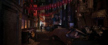 Movie still from “Luther: The Fallen Sun” (2023), directed by Jamie Payne – A person walking down a street near a building; Extreme Wide shot, High angle