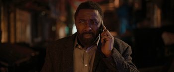 Movie still from “Luther: The Fallen Sun” (2023), directed by Jamie Payne – A man in a suit talking on a cell phone; Close Up shot, High angle