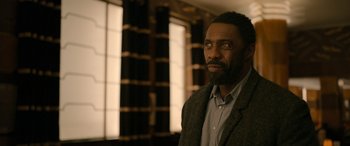 Movie still from “Luther: The Fallen Sun” (2023), directed by Jamie Payne – A man with a beard is standing in front of a window; Close Up shot, Over the shoulder angle