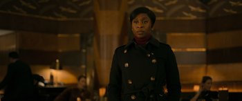 Movie still from “Luther: The Fallen Sun” (2023), directed by Jamie Payne – A woman in a black coat standing next to a wall; Medium shot, Over the shoulder angle