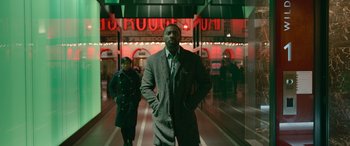 Movie still from “Luther: The Fallen Sun” (2023), directed by Jamie Payne – A man in a suit and tie standing in front of a building; Medium shot, Low angle