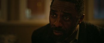 Movie still from “Luther: The Fallen Sun” (2023), directed by Jamie Payne – A man's face in a dark room; Close Up shot, High angle