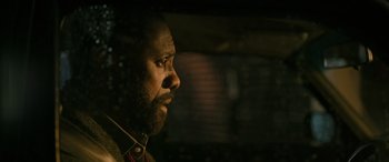 Movie still from “Luther: The Fallen Sun” (2023), directed by Jamie Payne – A person wearing headphones looking off into the distance; Close Up shot, Over the shoulder angle