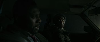 Movie still from “Luther: The Fallen Sun” (2023), directed by Jamie Payne – Two men sitting in the back seat of a car; Close Up shot, Over the shoulder angle