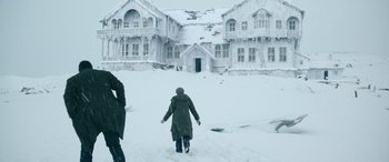 Movie still from “Luther: The Fallen Sun” (2023), directed by Jamie Payne – Two people walking in the snow near a large house; Wide shot, Low angle