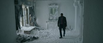 Movie still from “Luther: The Fallen Sun” (2023), directed by Jamie Payne – A man in a suit and tie walking through a snow covered room; Wide shot, High angle