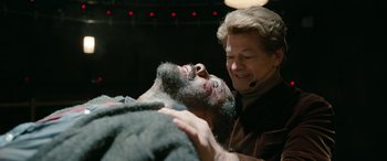 Movie still from “Luther: The Fallen Sun” (2023), directed by Jamie Payne – An older woman is shaving a man's beard; Close Up shot, Over the shoulder angle