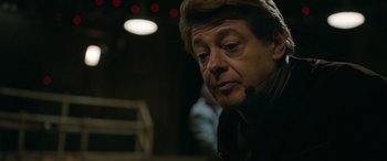 Movie still from “Luther: The Fallen Sun” (2023), directed by Jamie Payne – An older man wearing a headset looking at something; Close Up shot, Over the shoulder angle