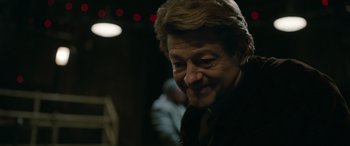 Movie still from “Luther: The Fallen Sun” (2023), directed by Jamie Payne – A person smiling at the camera; Close Up shot, Over the shoulder angle