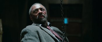Movie still from “Luther: The Fallen Sun” (2023), directed by Jamie Payne – A man with a beard and a tie on a swing; Close Up shot, Low angle