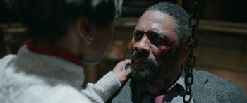 Movie still from “Luther: The Fallen Sun” (2023), directed by Jamie Payne – A woman putting makeup on the face of a man; Close Up shot, Over the shoulder angle