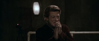 Movie still from “Luther: The Fallen Sun” (2023), directed by Jamie Payne – A man with long brown hair is holding his hands in front of his face; Close Up shot, Over the shoulder angle