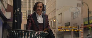 Movie still from “Lyle, Lyle, Crocodile” (2022), directed by Will Speck – A man with long hair is sitting on a park bench; Medium shot, Low angle