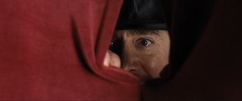 Movie still from “Lyle, Lyle, Crocodile” (2022), directed by Will Speck – A man peeking out from behind a red blanket; Extreme Close Up shot, Low angle