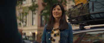 Movie still from “Lyle, Lyle, Crocodile” (2022), directed by Will Speck – A woman standing in front of a building with trees in the background; Close Up shot, Over the shoulder angle