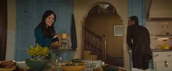 Movie still from “Lyle, Lyle, Crocodile” (2022), directed by Will Speck – A woman is standing at a dining room table; Medium shot, Over the shoulder angle