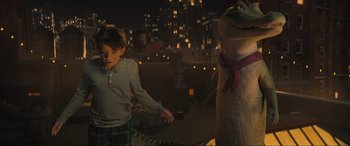 Movie still from “Lyle, Lyle, Crocodile” (2022), directed by Will Speck – A young boy standing in front of a stuffed alligator in a city at night; Medium shot, Over the shoulder angle