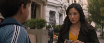 Movie still from “Lyle, Lyle, Crocodile” (2022), directed by Will Speck – A woman is holding a cell phone while standing on the sidewalk; Close Up shot, Over the shoulder angle