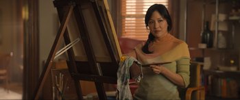 Movie still from “Lyle, Lyle, Crocodile” (2022), directed by Will Speck – A woman holding a paintbrush in front of an easel; Medium shot, Over the shoulder angle