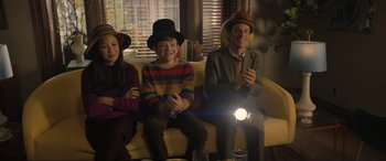 Movie still from “Lyle, Lyle, Crocodile” (2022), directed by Will Speck – A group of people sitting next to each other on a couch; Medium shot, Over the shoulder angle