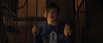 Movie still from “Lyle, Lyle, Crocodile” (2022), directed by Will Speck – A young boy is behind bars in a jail cell; Medium shot, Low angle