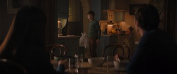 Movie still from “Lyle, Lyle, Crocodile” (2022), directed by Will Speck – A young boy standing in a kitchen holding a bag; Medium shot, Over the shoulder angle