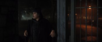 Movie still from “Lyle, Lyle, Crocodile” (2022), directed by Will Speck – A man leaning against a wall wearing a hat; Medium shot, Over the shoulder angle