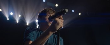 Movie still from “Lyle, Lyle, Crocodile” (2022), directed by Will Speck – A man holding a microphone up to his face; Close Up shot, Low angle