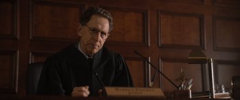 Movie still from “Lyle, Lyle, Crocodile” (2022), directed by Will Speck – A man in a judge's robe is sitting in front of a microphone; Close Up shot, Low angle