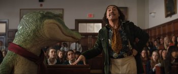 Movie still from “Lyle, Lyle, Crocodile” (2022), directed by Will Speck – A man in a courtroom with a fake alligator on his arm; Medium shot, Low angle