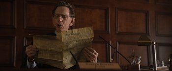 Movie still from “Lyle, Lyle, Crocodile” (2022), directed by Will Speck – A man holding an old newspaper while standing at a podium; Close Up shot, Low angle
