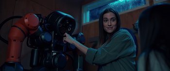 Movie still from “M3GAN” (2022), directed by Gerard Johnstone – A woman standing in front of a machine; Medium shot, Over the shoulder angle